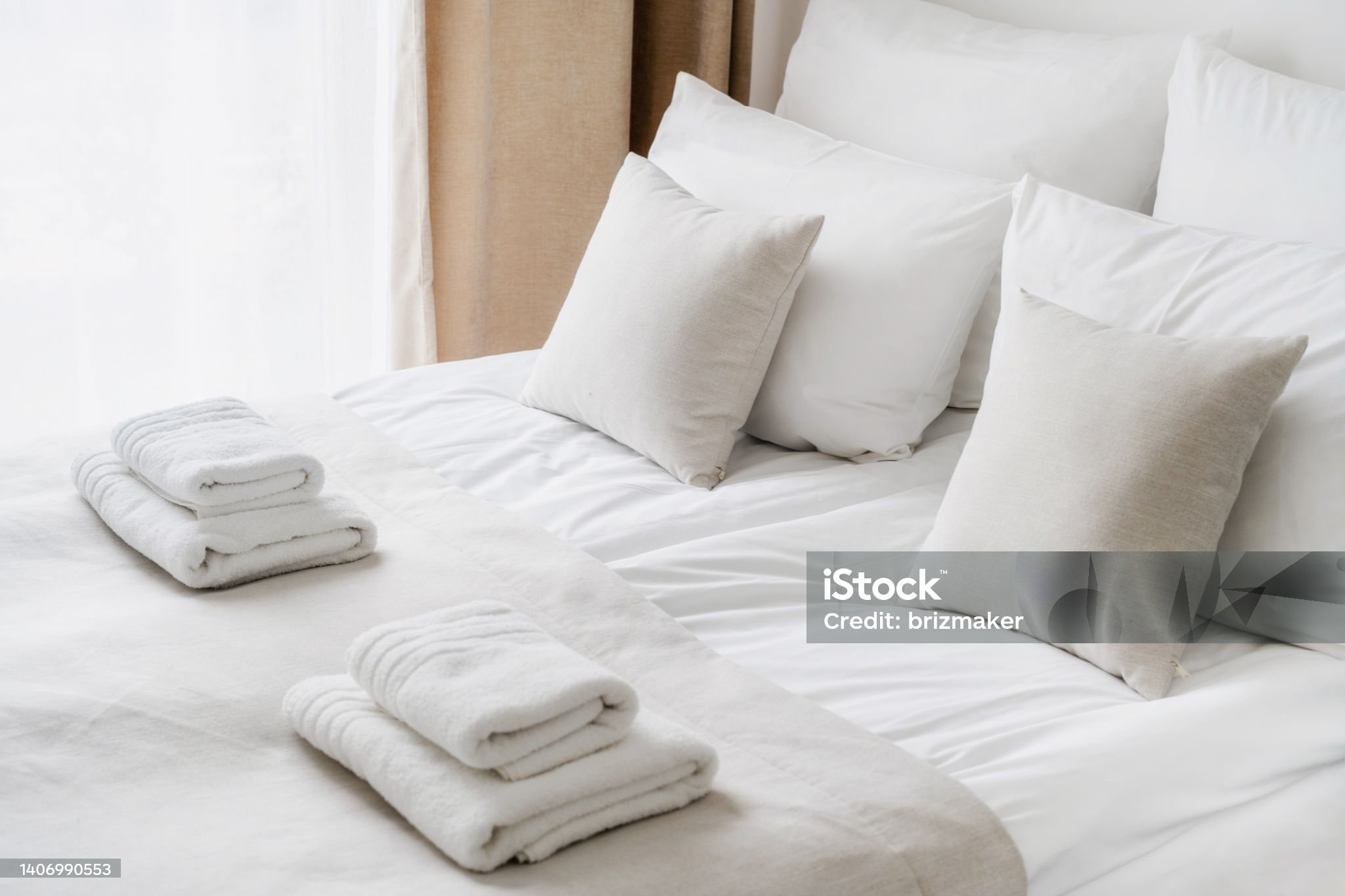 Cropped view of white bedclothes and towels on bed in comfortable hotel room, hypoallergenic pillows, personal comfort idea, bedding concept, bathroom details